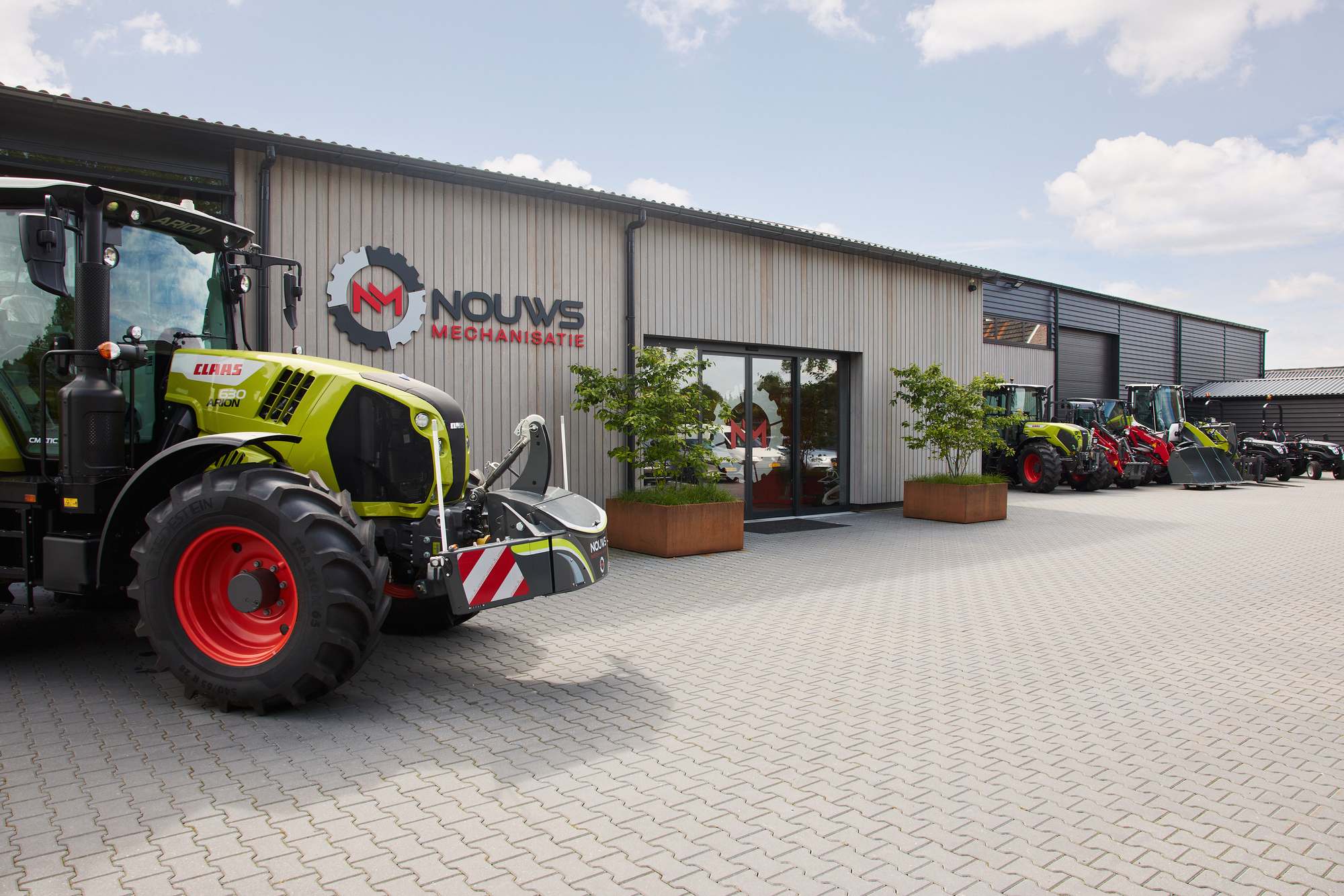 Het pand van Nouws Mechanisatie in Rijsbergen met een Claas-tractor voor de deur