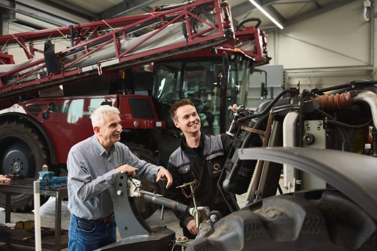 Een ervaren en een jonge monteur werken samen aan een machine