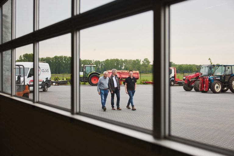 Drie mannen lopen over het terrein van Nouws Mechanisatie